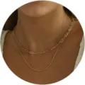 Dettaglio ravvicinato di una collana dorata a due strati con catena a graffetta e serpente. - Catena a Graffetta e Catena a Serpente Sottile