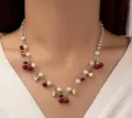 Dettaglio di una collana con ciliegie pendenti, perle finte e cuori dorati raffinati - Stile Misto Ciliegia Cuore / Oro