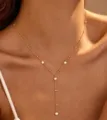 Primo piano di una collana a Y dorata con cristalli pendenti e piccole perle. - Stile Perline di Cristallo (03 Bordo Vetro Oro) / Finitura in Vetro Oro