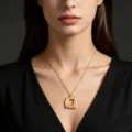 Primo piano di una collana dorata con pendente geometrico indossata su uno scollo nero. - Stile Catena Sottile (02) / Oro