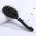 Anti-static massage hairbrush in black with gold accents on a clean marble surface - Oval Black