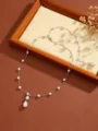 Macro detail of an elegant pearl fringe necklace with a teardrop pendant on a wooden display - Silver