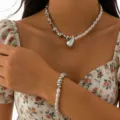 Close-up of metallic teardrop pendant necklace and matching pearl bracelet on a model - Teardrop Pendant Necklace And Bracelet Set (01) / Silver