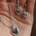 Elegante set di gioielli con collana e orecchini a forma di cuore d'argento in mano - 02 Set Collana e Orecchini a Cuore / Argento