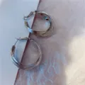 Close-up detail of silver-colored multi-layer hoop earrings with textured background. - Multi-layer Circle Style (E0984) / Silver