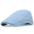 Detailed close-up of a light blue cotton flat cap featuring white contrast stitching. - Light Blue