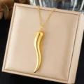 Close-up of a gold-plated stainless steel chili pendant necklace on a beige jewelry box - Chili Pendant Style (N4384) / Gold (N4384)