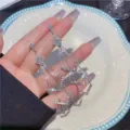 Vista dettagliata di orecchini geometrici a nappa in argento con strass scintillanti in mano - Stile Strass Rombo Geometrico (E1666) / Argento