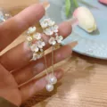 Dettaglio degli orecchini floreali in stile francese con pendenti di perle e catena dorata. - Stile Pendente Perla Piccolo Fiore Bianco (E3139) / Oro