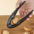 Ergonomic black nutcracker and chestnut opener tool shown cracking a walnut - Black