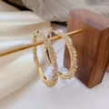 Close-up of sparkling gold crystal hoop earrings displayed on a rustic wooden stand - Full Rhinestone Large Hoop Style (E0207) / Gold