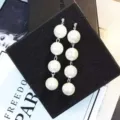 Elegant long drop earrings with four white pearls on a black jewelry box display. - Four-Bead Tassel Silver Style (E0196)
