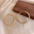 Elegant gold textured hoop earrings displayed on satin fabric background - Large Hammered Gold Hoop Style (E0270)