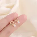 Elegant minimalist gold-tone twisted loop stud earrings with white pearl accents - Crossed Artificial Pearl Stud Style (E0189) / Gold