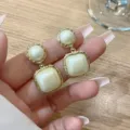 Elegant vintage gold-tone earrings with square and round cream faux pearls held in hand - Vintage Geometric Artificial Pearl Style (E3185) / Gold