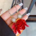 Detailed view of elegant long earrings featuring red flower petals and white pearls - Pearl Tassel Style (E1182) / Gold/Red