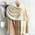 Gros plan d'une écharpe à carreaux crème chaude avec des bords à franges sur un manteau. - Z256 / Blanc Cassé
