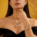 Primo piano di elegante set collana e bracciale di perle argentate con pendente a cuore su modella - set collana e bracciale / Argento