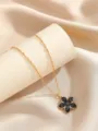 Dettaglio di una collana a catena dorata con un elegante ciondolo a fiore in smalto nero - Nero