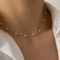 Dettaglio di una collana girocollo minimalista con perle dorate - Stile Semplice / Oro