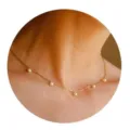 Gedetailleerde close-up van een delicate gouden ketting met kleine parels in de nek. - Stijl 4 / Goud
