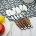 Close-up detail of rosewood handle stainless steel spoon set with iconic bee motif - 6-Piece Dinner Spoons