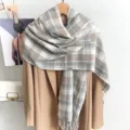 Gedetailleerd overzicht van een warme grijs-witte geruite wintersjaal over een beige jas - 67*180 / Grijs