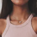 Macro-opname van een minimalistische zilveren hartketting gedragen door een model in roze - Eenvoudige Hart Sleutelbeen Ketting (5)