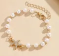 Elegante bracciale a stella marina dorata con perle bianche e cristalli scintillanti. - Bracciale