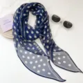 Vista detallada de un pañuelo de seda azul marino con lunares blancos y accesorios elegantes. - Azul Marino Lunares
