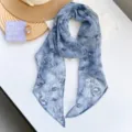 Detalle de bufanda ligera de gasa con flores azules para elegantes atuendos femeninos - Flor Azul Bruma