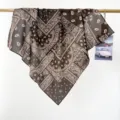 Vue détaillée d'un bandana paisley en coton marron drapé sur une tige dorée - Brun Foncé Paisley