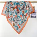 Detail view of a lightweight cotton square scarf with vibrant orange and blue leaf patterns. - RY-09