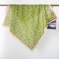 Close-up detail of a green floral print cotton square scarf hanging on a minimalist gold rod - RY-16
