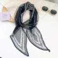 Primer plano de bufanda de gasa negra con estampado floral blanco y encaje elegante. - Borde Ondulado Negro