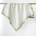 Gros plan d'un foulard carré en coton vert clair à pois suspendu à une tringle dorée - Vert Clair Pois