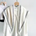 Detail view of a large triangular scarf with geometric border draped over a white blouse - 87*130CM / Off White