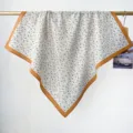 Gros plan d'un foulard carré en coton à imprimé floral cachemire avec une bordure orange éclatante. - Bleu et Jaune Floral