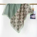 Vue détaillée d'un foulard en coton à motifs pied-de-poule vert et paisley sur une barre dorée. - Vert Herbe Pied-de-poule