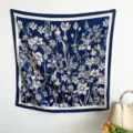 Detailed view of a navy blue square scarf with white vintage floral patterns hanging. - RY-42