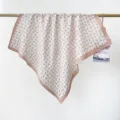 Detail of a white cotton square scarf with pink floral print draped on a gold rod. - RY-53
