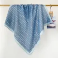 Détail d'un foulard carré bleu clair à pois drapé sur une tringle en bois naturel. - Bleu Clair et Rose Pois