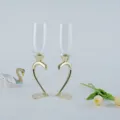 Elegant crystal champagne flutes with golden heart-shaped stems and decorative wedding props - Gold