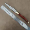Laguiole steak knife with wooden handle and serrated blade shown next to a ruler for scale. - Steak Knife