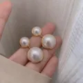 Elegant double pearl drop earrings with gold-toned plating for women shown held in hand - Double Pearl Vertical Style (E0833)