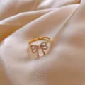 Detailed close-up of a gold-colored open ring with a sparkling bowknot design - Pave Rhinestone Bow Style (J0008) / Adjustable Open