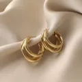 Macro detail of elegant triple hoop gold earrings on champagne silk background - Triple C-Shape Ring Style (E0094)