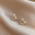 Detail of gold-toned triangular stud earrings with elegant white inlay texture - Geometric Triangle Style (E0095)