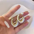Elegant gold-plated U-shaped earrings with a pearl-white finish in a hand-held view. - Gold U-Shaped Colorblock Pearl White Style (E1720)