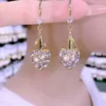 Elegante herzförmige goldfarbene Tropfenohrringe mit funkelnden blauen Kristallen. - Weiß